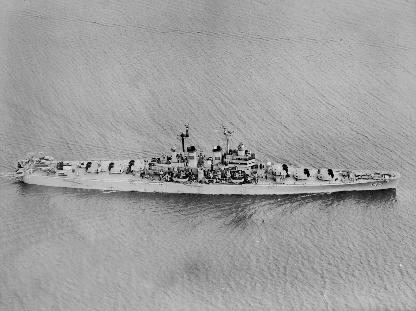 The U.S. Navy light cruiser USS Roanoke (CL-145) underway off the Philadelphia Naval Shipyard, Pennsylvania (USA), in January 1950. Note the automobiles and the Sikorsky HO3S helicopter on the fantail.