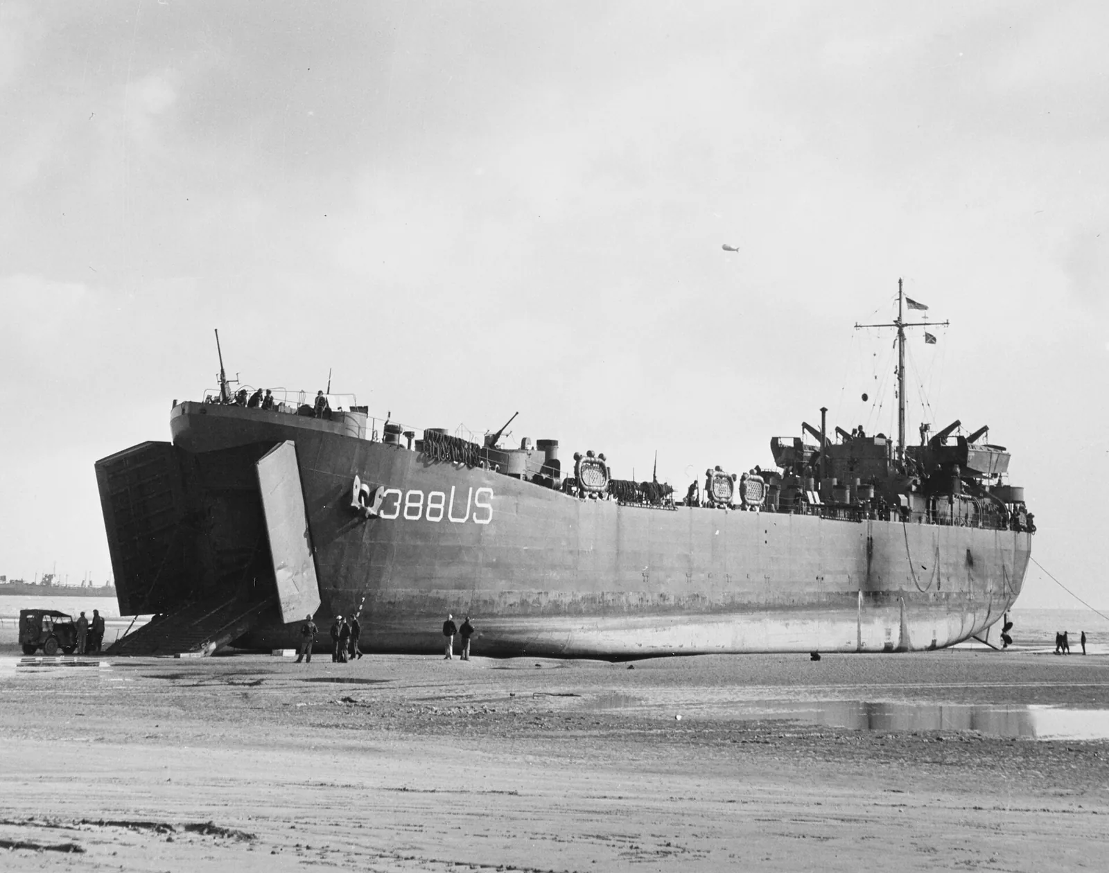 USS LST-388 unloads on a Normandy beach at low tide, 12 June 1944. Note barrage balloon overhead. Taken by Combat Photo Unit Eight (CPU-8). Official U.S. Navy Photograph, now in the collections of the National Archives.